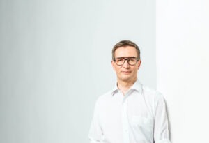 Oras tynkkynen nojaamassa seinÃ¤Ã¤n valkoisessa kauluspaidassa.