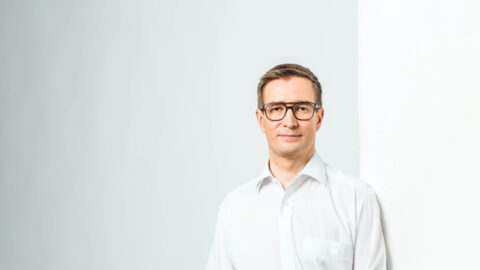Oras tynkkynen nojaamassa seinÃ¤Ã¤n valkoisessa kauluspaidassa.